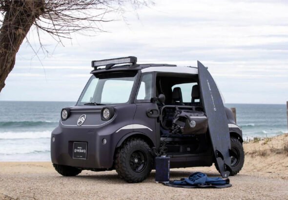 Imagen del Citroën Ami Buggy Rip Curl en la playa sobre la arena y el mar de fondo en un día soleado. Vista del exterior del coche.
