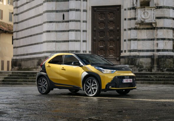 Imagen del nuevo Toyota Aygo X Híbrido de color amarillo y techo negro en una calle de día