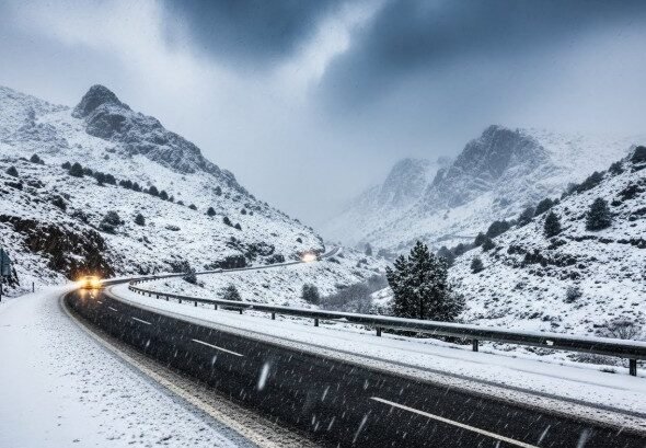 Imagen de una carretera entre montañas cubiertas de nieve por la Borrasca Francis