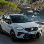 El SEAT Arona consolida su hegemonía en España como el SUV urbano más vendido por séptimo año consecutivo Imagen del seat arona por una carretera con vistas al mar.