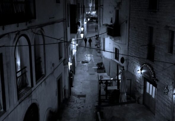 Calle oscura con personas caminando.