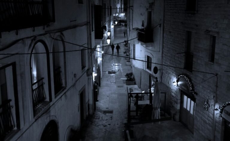 Calle oscura con personas caminando.