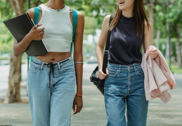 Estudiantes paseando por un parque con carpeta y mochila de estudio.
