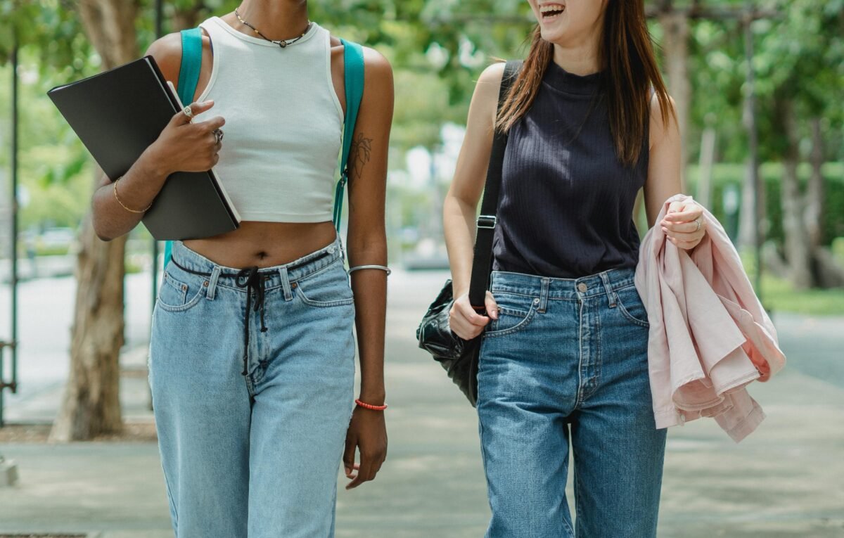 Estudiantes paseando por un parque con carpeta y mochila de estudio.