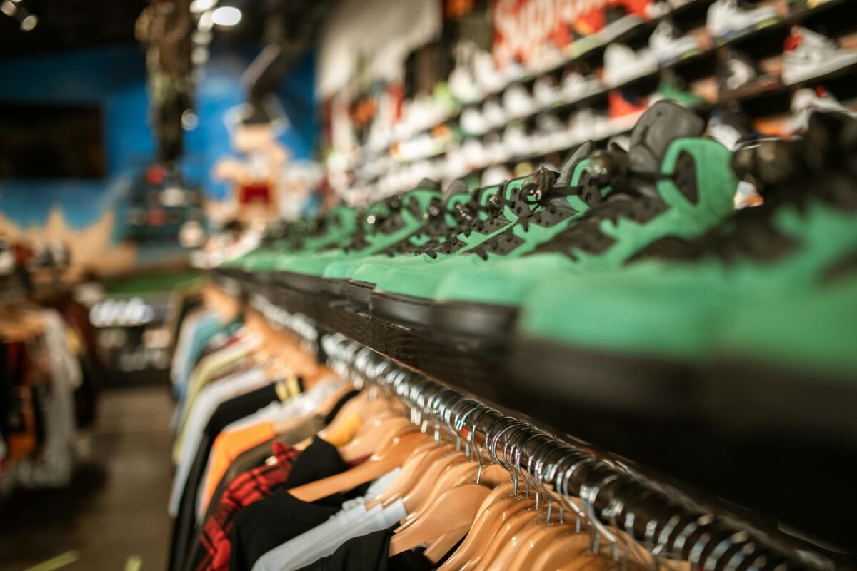 Zapatillas verdes en tienda deportiva con ropa en percheros.