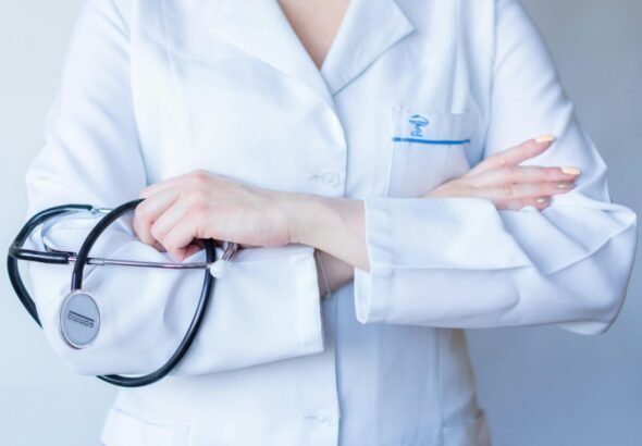 Médico con los brazos cruzados y su bata blanca.