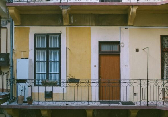 Imagen de la entrada de una vivienda en una finca de color amarillo.