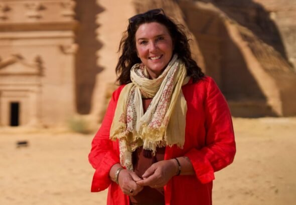 Mujer en desierto con monumentos antiguos.