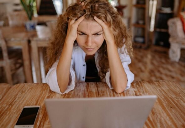 Mujer estresada frente a computadora con ansiedad.