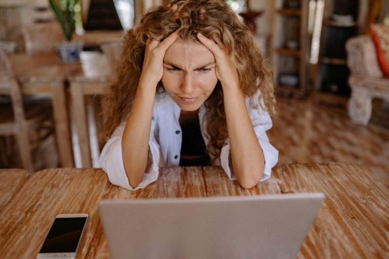 Mujer estresada frente a computadora con ansiedad.
