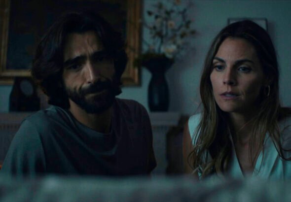 Pareja sentada en un ambiente oscuro.
