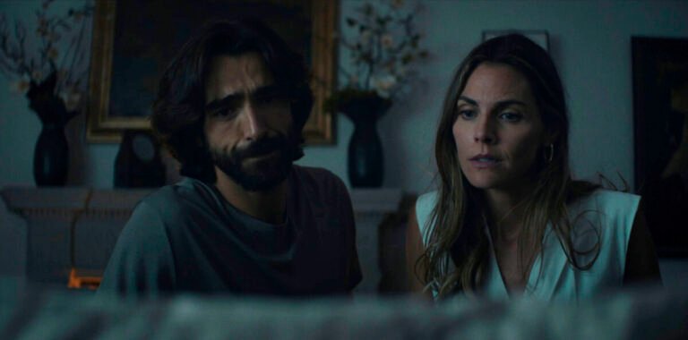 Pareja sentada en un ambiente oscuro.