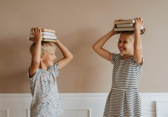 Niños sosteniendo libros sobre la cabeza.