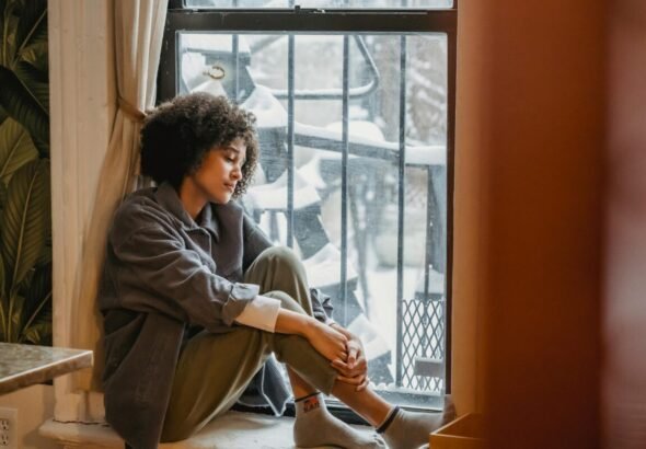 Mujer mirando por la ventana nevada.