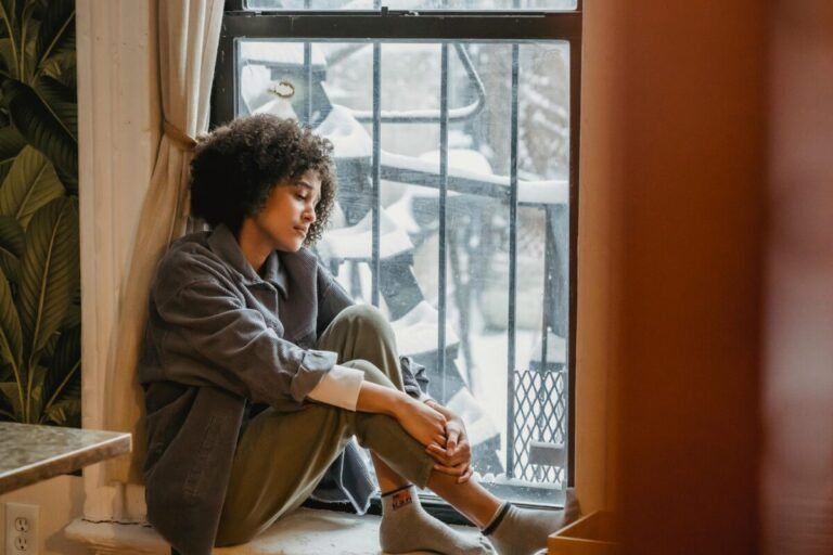 Mujer mirando por la ventana nevada.