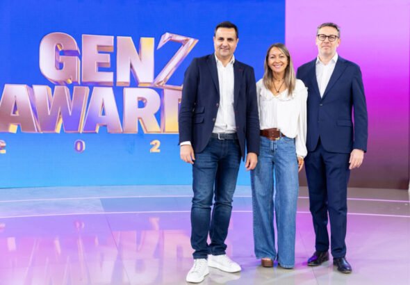 Fotografía de la presentación de los GenZ Awards. Aparecen en plano medio Luis Movilla, Marta Hernando y Davide Mondo, directivos de Publiespaña y Mediaset España, posando sonrientes frente a un fondo corporativo con el logotipo de los premios. Visten ropa formal de negocios y la iluminación es de estudio profesional.