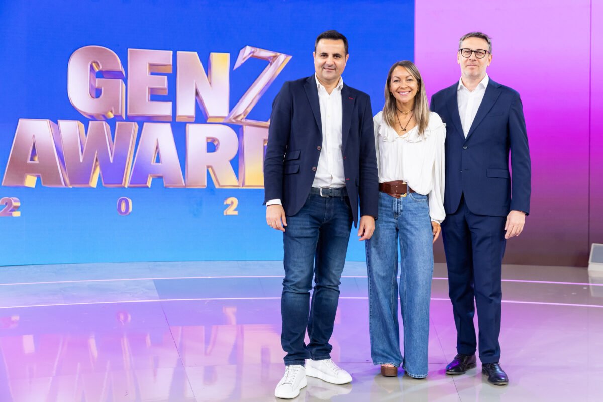 Fotografía de la presentación de los GenZ Awards. Aparecen en plano medio Luis Movilla, Marta Hernando y Davide Mondo, directivos de Publiespaña y Mediaset España, posando sonrientes frente a un fondo corporativo con el logotipo de los premios. Visten ropa formal de negocios y la iluminación es de estudio profesional.