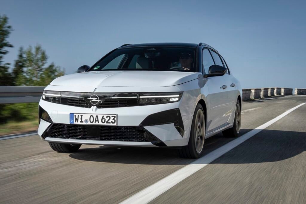 Del éxito de los 90 al rayo eléctrico: El viaje épico del Opel Astra Nuevo Opel Astra 2026. imagen exterior en color blanco y negro circulando por carretera