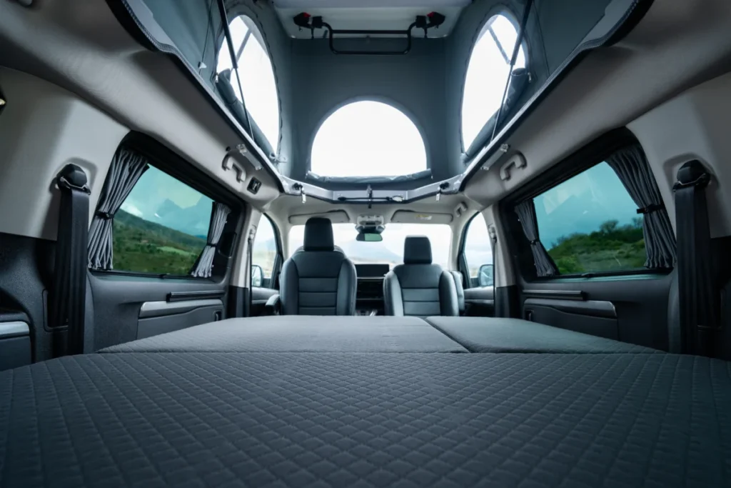¿Tu casa o tu coche? La libertad total del nuevo Opel Zafira de Tinkervan Nuevo Opel Zafira 2026 con la imagen del espacio de la cama estirada y las vistas del techo abierto con espacio para entrada de luz