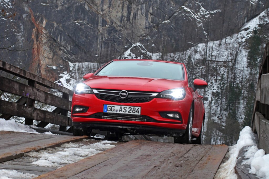 Del éxito de los 90 al rayo eléctrico: El viaje épico del Opel Astra Imagen del Opel Astra K exterior de color rojo circulando por zona de montaña