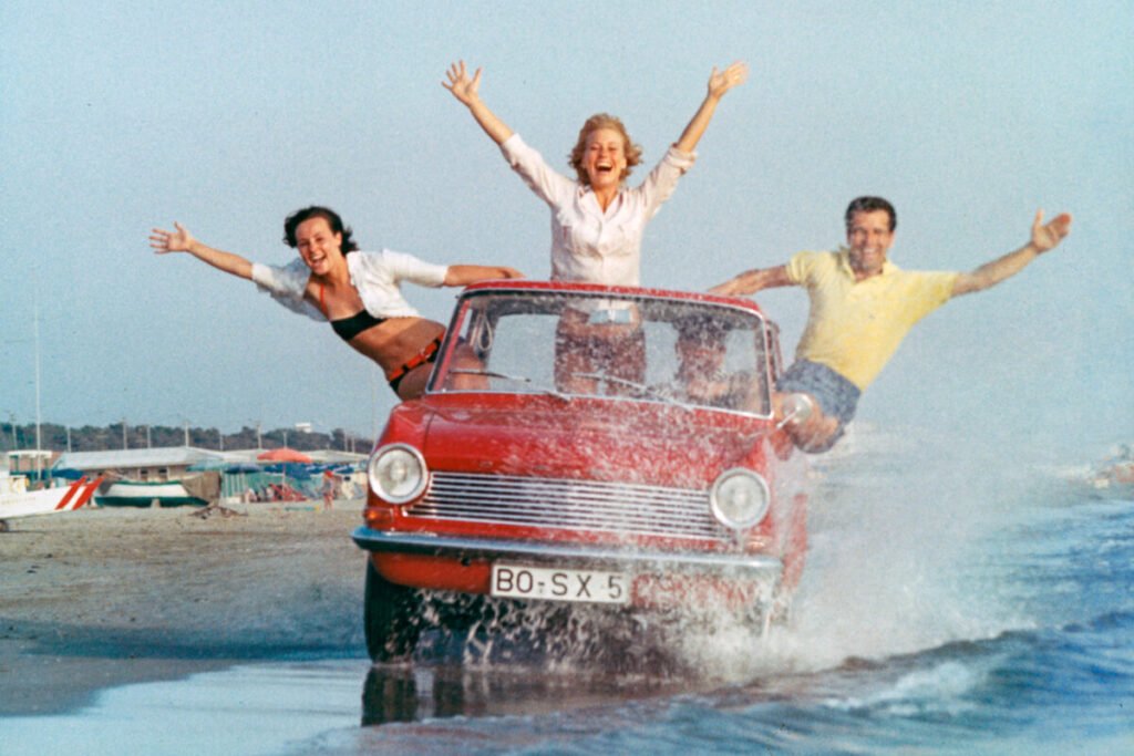 El coche que puso a rodar a un país: La legendaria saga del Opel Kadett Imagen del Opel Kadett A 1962 exterior circulando por la orilla de la playa
