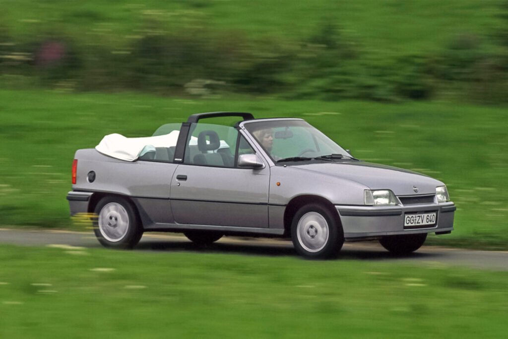El coche que puso a rodar a un país: La legendaria saga del Opel Kadett Imagen del Opel Kadett Cabrio de 1989 de color gris por una zona rural