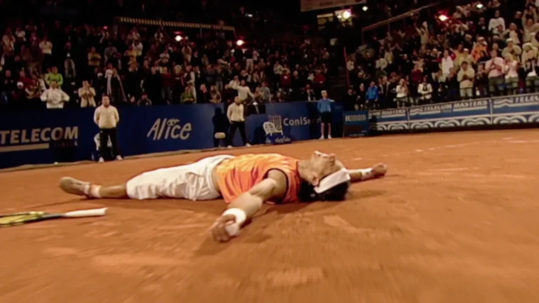Imagen que muestra a Rafa Nadal en una pista de tierra batida tirado en el suelo con la raqueta a un lado