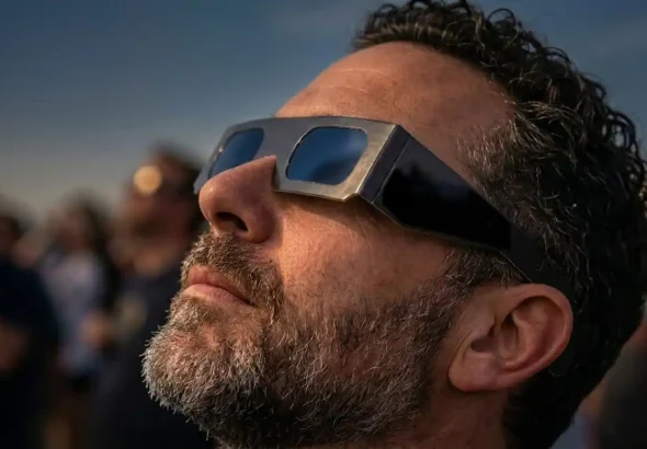 Una persona está observando con las gafas el eclipse solar en España de 2026