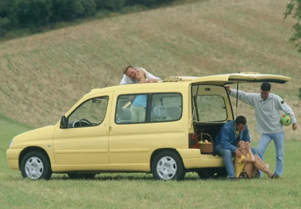 Imagen de la Citroën Berlingo de archivo, de color amarillo. Vista del exterior con el portón trasero abierto.