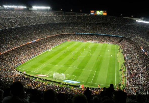 Imagen que muestra un campo de fútbol abarrotado de gente con los fútbolistas posicionados en una de las alineaciones del fútbol actual