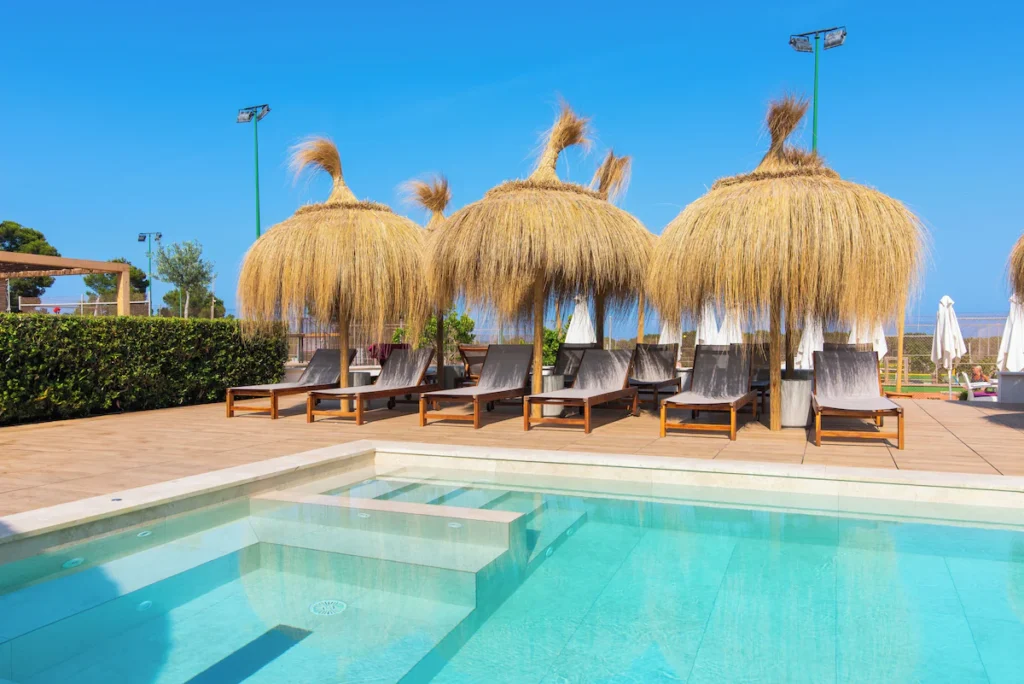 Olvídate del dolor de cabeza de organizar tus vacaciones: estos tres chollos a las Baleares te lo dan todo hecho Imagen de la piscina con sombrillas del Hotel Na Taconera