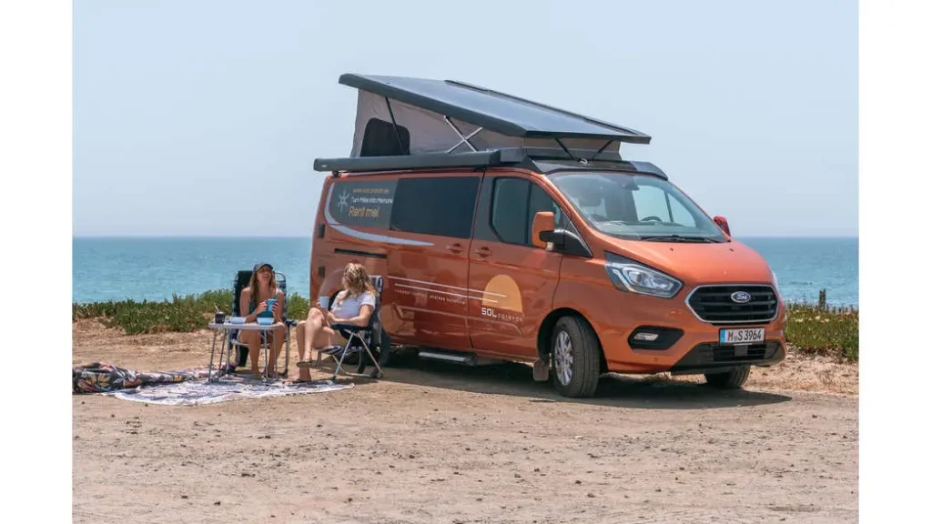 Ni hotel ni apartamento: la tendencia que arrasa para viajar por Andalucía este verano Imagen que muestra el exterior de la autocaravana Karmann Duncan 545 de color naranja, aparcada en una zona de playa en verano