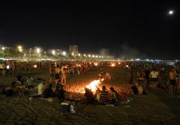 Recreación digital de la Noche de San Juan en Valencia con gente en la playa y hogueras