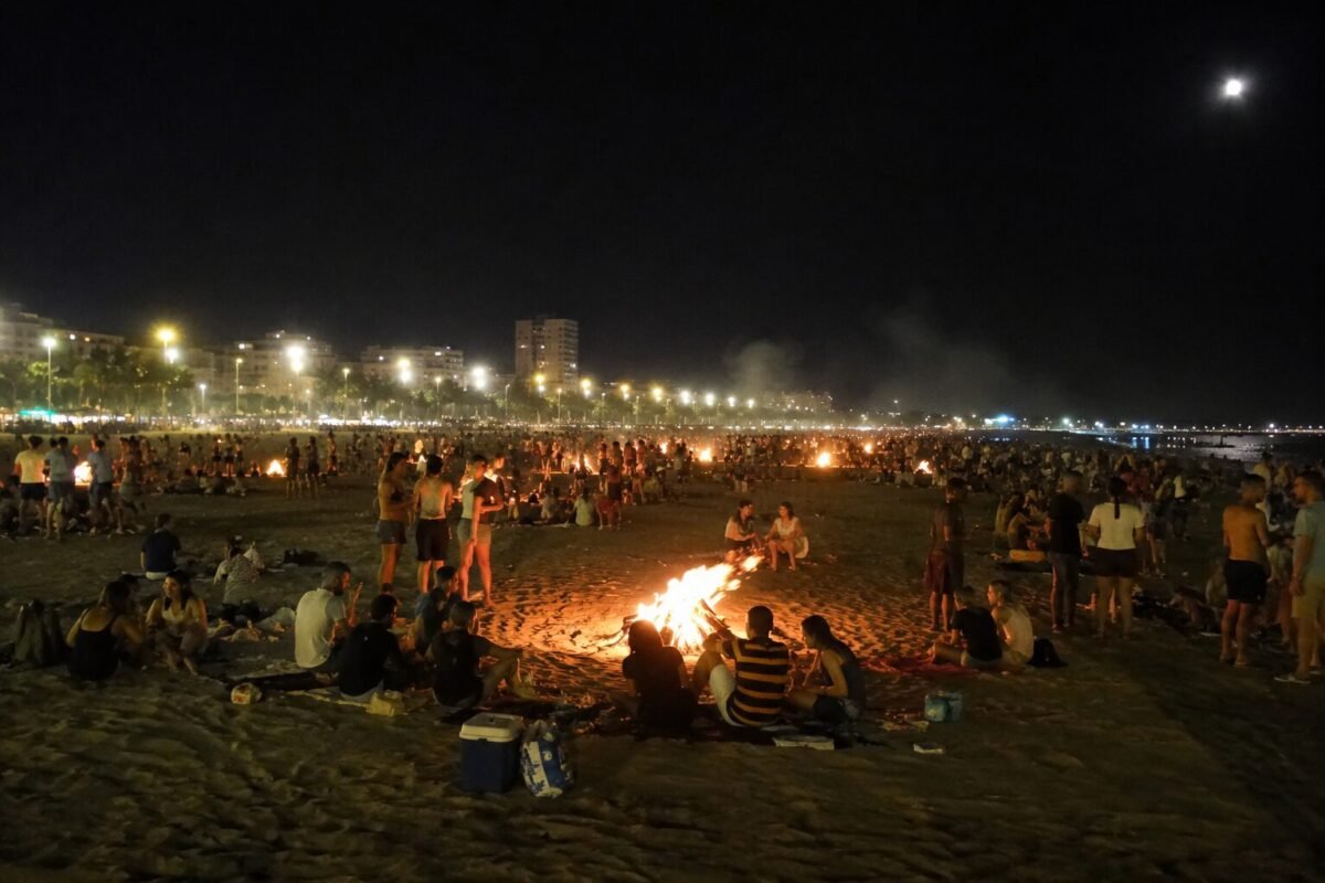Recreación digital de la Noche de San Juan en Valencia con gente en la playa y hogueras