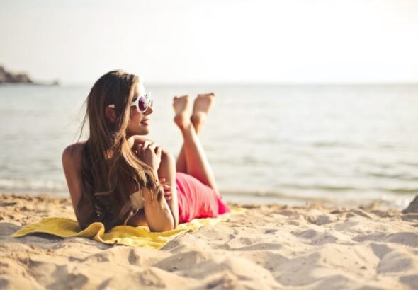 Imagen que muestra a una chica en la playa con las sandalias fuera de los pies.