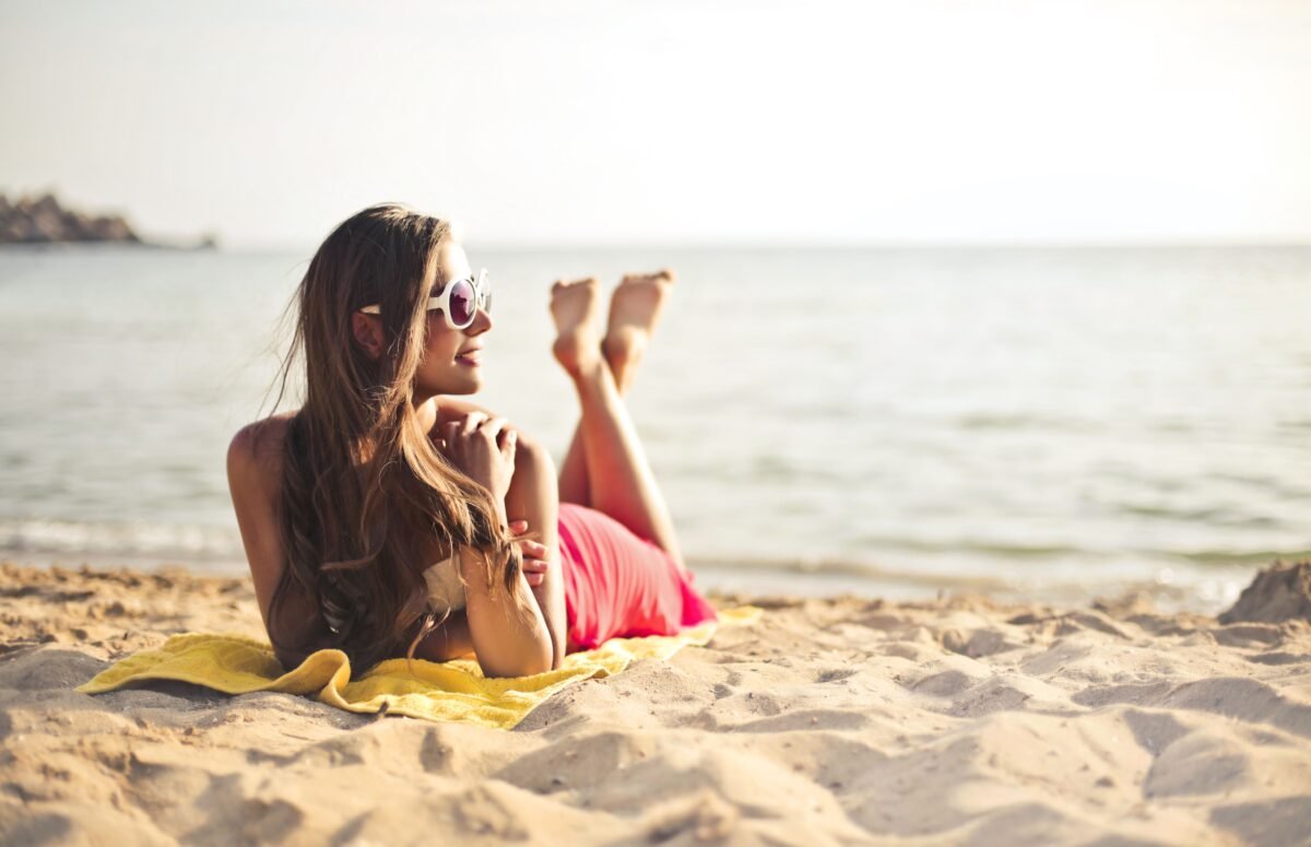 Imagen que muestra a una chica en la playa con las sandalias fuera de los pies.