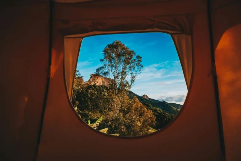 Imagen del interior de una tienda de campaña con vistas por la ventana a una montaña en un festival