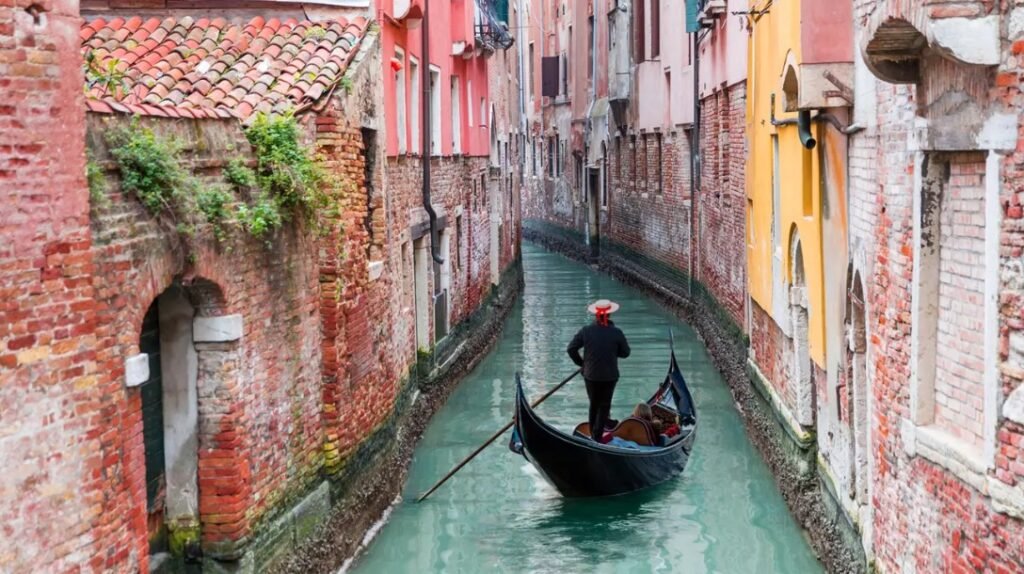 Así puedes viajar a Venecia con vuelos y hotel por menos de 300 Imagen de un canal estrecho de Venecia con una góndola paseando por el agua