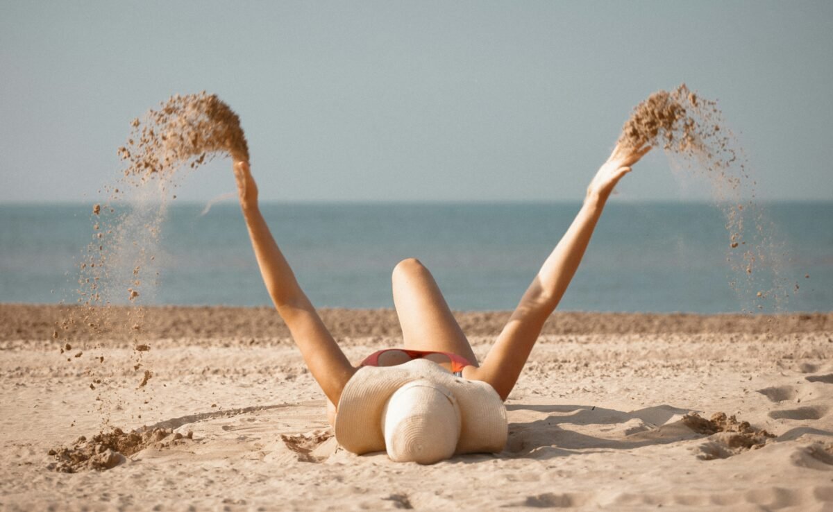 Imagen que muestra a una chica en la arena de la playa tumbada con uno de los bañadores tendencia de verano