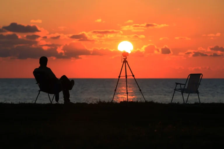 Imagen que muestra un eclipse solar y una persona sentada en la playa observando