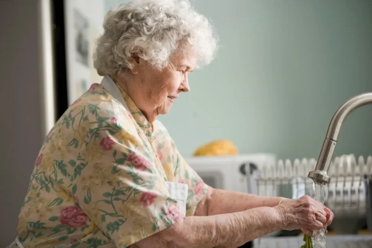Anciana lavando verduras en casa