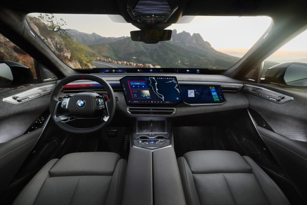 El nuevo BMW X5 viene con todo: 5 motores distintos y una autonomía salvaje de 845 km Imagen que muestra el interior delantero con vistas al salpicadero con el volante y las pantallas , que cuenta con tapiceria oscura del nuevo BMW X5 2026