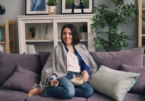 Movistar Plus estrena grandes documentales este julio. Persona en el sofá de su casa con palomitas viendo el streaming