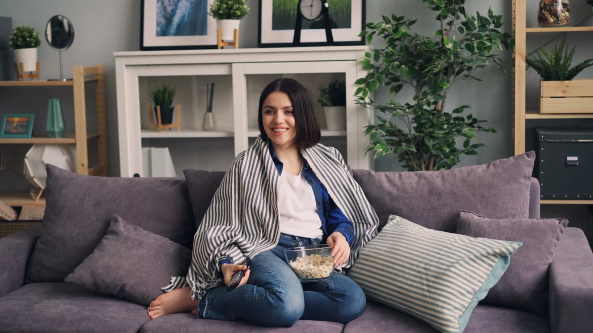 Movistar Plus estrena grandes documentales este julio. Persona en el sofá de su casa con palomitas viendo el streaming