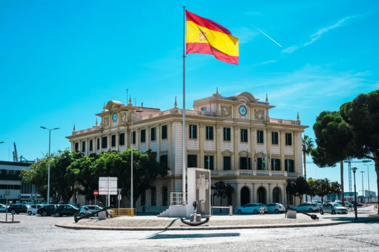 La regularización extraordinaria se ilustra con un edificio en España y su bandera. Imagen de recurso.