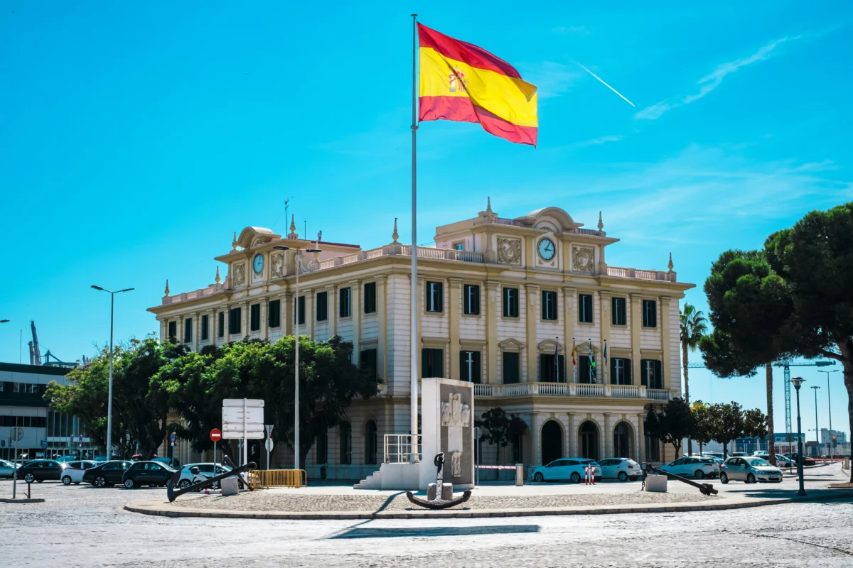 La regularización extraordinaria se ilustra con un edificio en España y su bandera. Imagen de recurso.