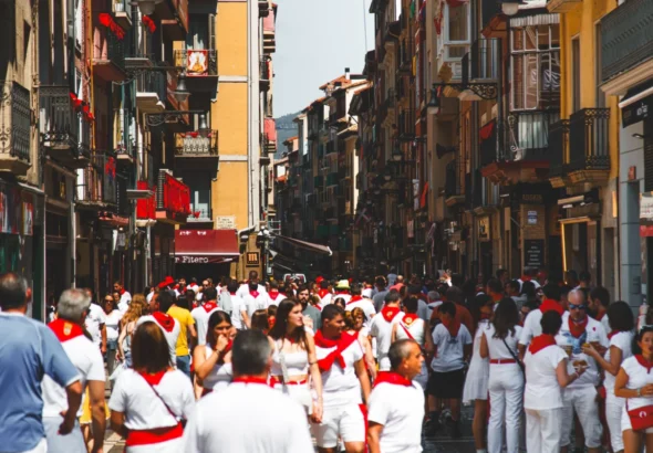 San Fermín en Pamplona, que muestra una calle llena de gente con el traje blanco y el pañuelo rojo.
