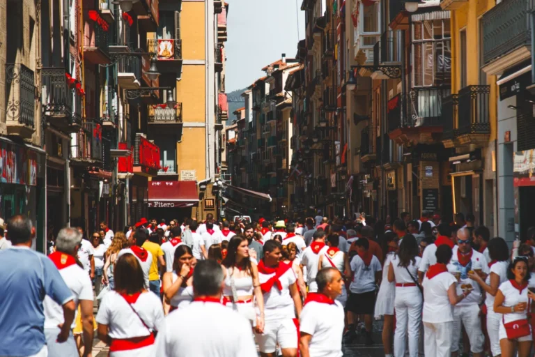 San Fermín en Pamplona, que muestra una calle llena de gente con el traje blanco y el pañuelo rojo.