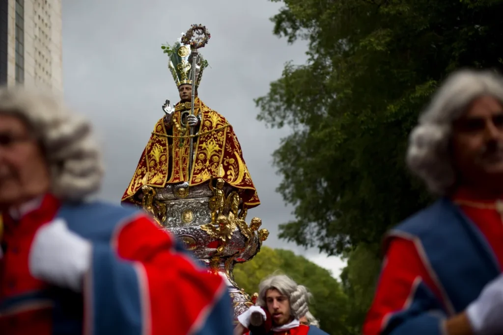 Sanfermines al descubierto: Viaja al corazón de la fiesta más salvaje y legendaria con su historia San Fermín muestra la procesión del Santo con la imagen en primer plano de este por una calle de Pamplona