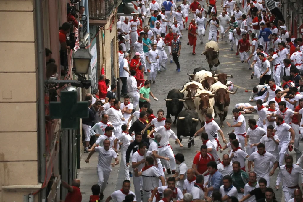 Sanfermines al descubierto: Viaja al corazón de la fiesta más salvaje y legendaria con su historia San Fermín, la imagen que muestra el encierro en la actualidad corriendo por las calles de Pamplona